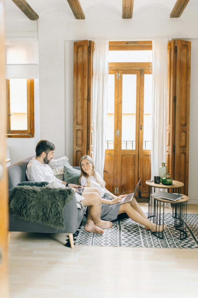 A couple working on laptops in a bright living room, embracing a remote work lifestyle.