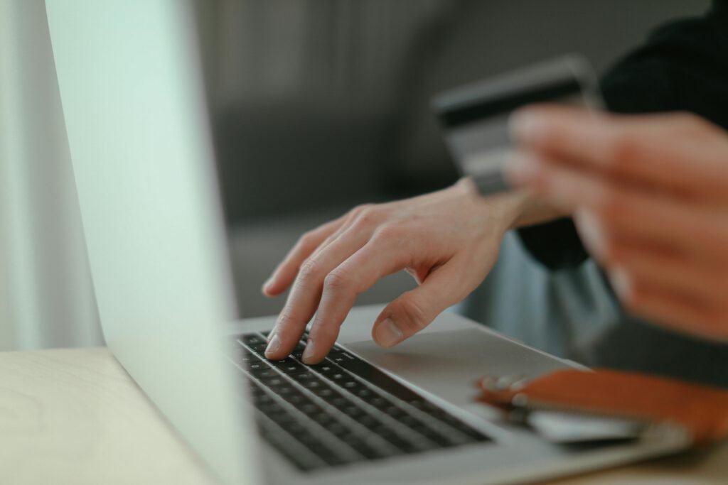 pexels photo 6633607 6633607 Close-up of hands holding a credit card and typing on a laptop keyboard for online shopping.
