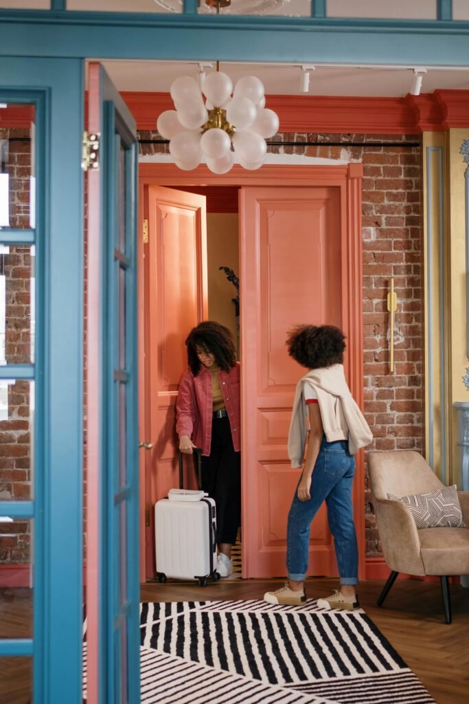 pexels photo 7128343 7128343 Two women arriving home with a suitcase, greeted by stylish interior design.